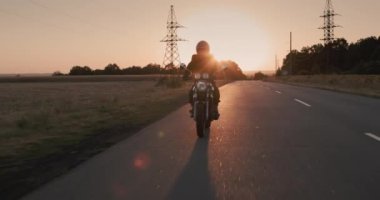 The silhouette of a motorcyclist, leaving the city at sunset. Escape concept