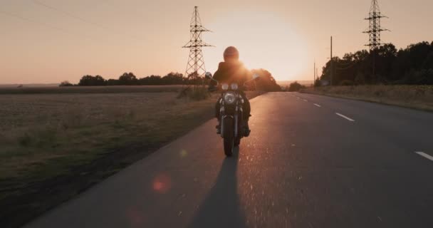 Die Silhouette eines Motorradfahrers, der die Stadt bei Sonnenuntergang verlässt. Fluchtkonzept — Stockvideo