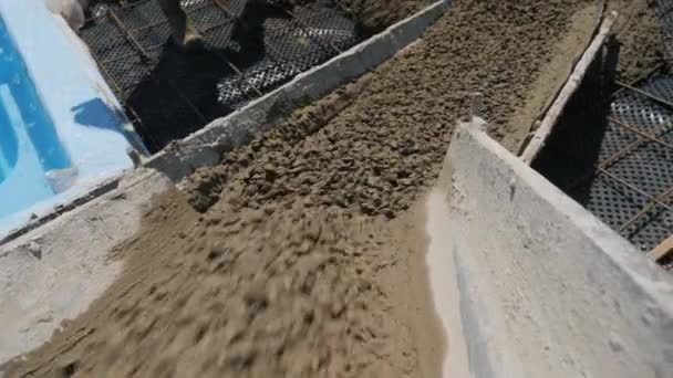 Concrete flows from the concrete mixer to the prepared base of reinforcement. Builders make paving around the pool — Stockvideo