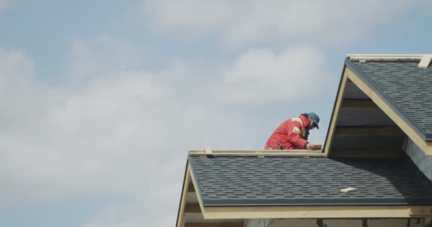 The builder is working on the roof of the house - laying shingles — 图库视频影像