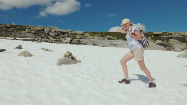 Eine Frau geht an einem klaren Sommertag durch den Schnee. Die Natur Norwegens und die Reise durch Skandinavien — Stockvideo