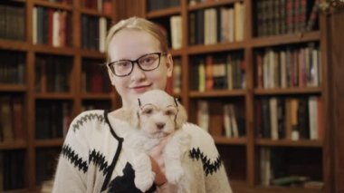 Kütüphanedeki iki okul çocuğu bir kız ve gözlüklü bir köpek yavrusu. Favori evcil hayvanlar ve eğitim.