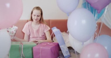 Kız bir sürü doğum günü hediyesi aldı, güzel kutuların yanındaki yatağa oturdu, balonların yanına..
