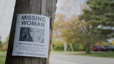 Kayıp bir genç kadın ilanı yolun yakınındaki bir direğe asılmış..