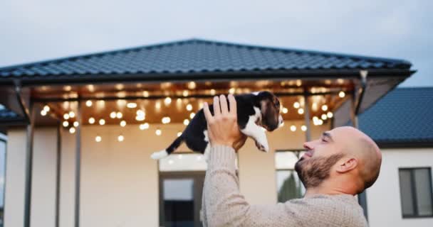 一个年轻人在他家门前和一只小狗玩耍 甜蜜的家 — 图库视频影像