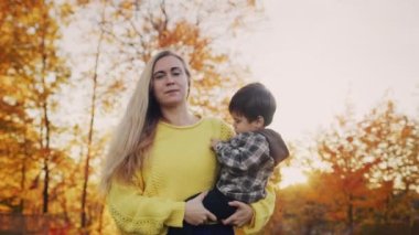 Annem kucağında bir bebek taşıyor, gün batımında güzel bir parkta yürüyor. 4k video