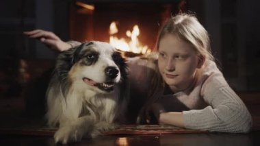 Köpek odanın zemininde yatıyor, şöminenin arkasında bir ateş yanıyor. Sıcaklık, rahatlık ve Noel tatili.
