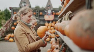 Mom and daughter buy pumpkins at the Halloween and Thanksgiving fair.