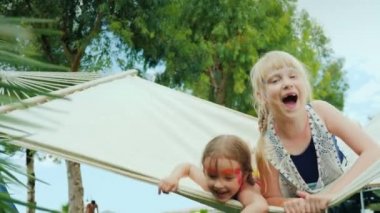 Little children with aqua-grim on their faces skate happily on a white cloth hammock on the beautiful green glade of the hotel.