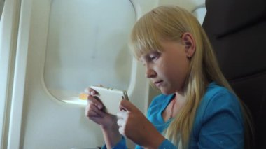 The child plays on the smartphone in the cockpit.
