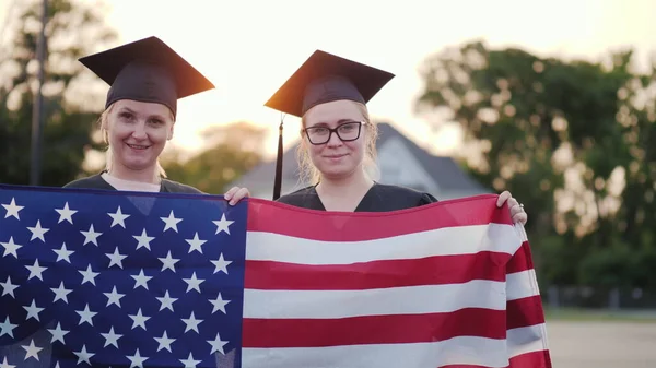 Két Főiskolai Diplomások Köpenyek Sapkák Amerikai Zászló — Stock Fotó