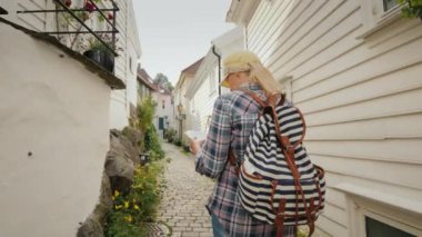 Elinde harita olan turist Norveç'te Bergen'in dar sokaklarında yürüyor. İskandinavya'da Tatil.