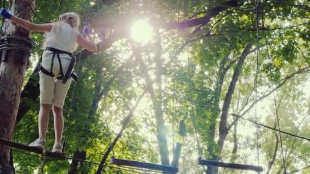 背の高い木の間には勇敢な子供が綱渡りをする 活動的な子供時代と楽しみ — ストック動画