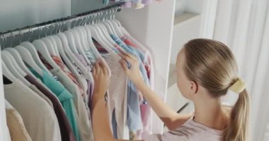 A teenager chooses a dress in the dressing room