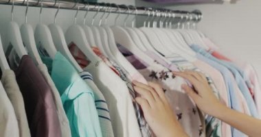 Hands of a child, chooses a dress on a coat hanger in the wardrobe.