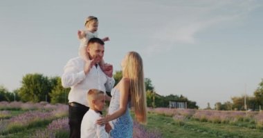 Portrait of a happy family in a lavender field, their house in the distance.
