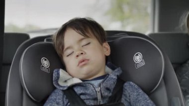 Two years old, the kid rides in a car seat and naps. Travelling with children.