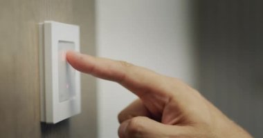 The homeowner regulates the temperature in the house on the electronic control panel.