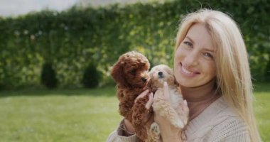 Portrait of a pregnant woman with puppies in her hands, standing in the backyard of the house.