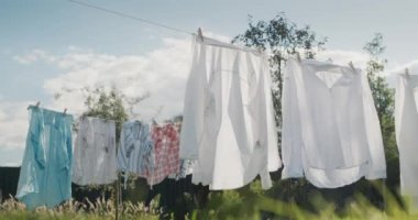 Kadın evin arka bahçesinde çarşafların kurumasını seyrediyor..