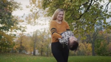 Genç ve mutlu bir anne çocuğunun etrafında döner ve yürüyüş yaparken iyi vakit geçirir. Günbatımının arka planına karşı