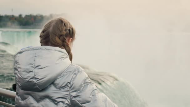 Een Meisje Een Warm Jasje Bewondert Majestueuze Niagara Watervallen Achteraanzicht — Stockvideo