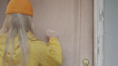 The child comes to get candy at the door of the house. Woman opens the door and gives a treat.