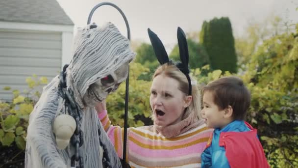 Maman Avec Bébé Dans Les Bras Près Squelette Qui Décoré — Video