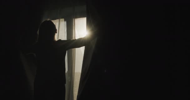 Silhueta Uma Mulher Que Abre Cortinas Blackout Iluminado Pelo Sol — Vídeo de Stock