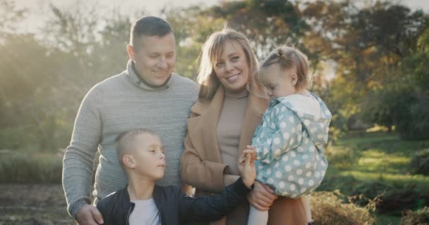 一个年轻健康的家庭的画像 一对夫妇和两个孩子 看着相机 站在秋天的公园里 — 图库视频影像