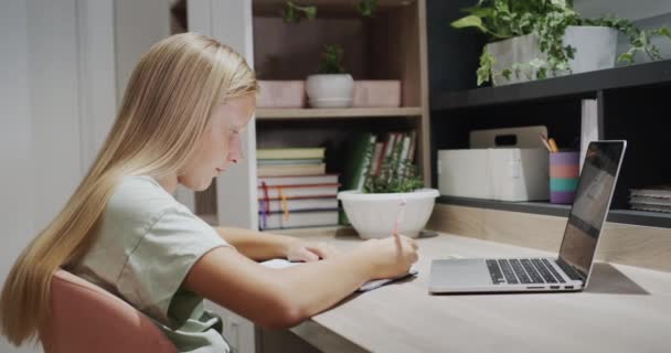 Egy Tinédzser Lány Egy Füzetbe Egy Asztalnál Egy Laptop Mellett — Stock videók