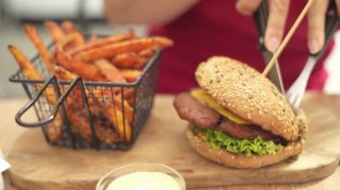 Genç kadın restoranın dışında lezzetli bir burger yiyor.