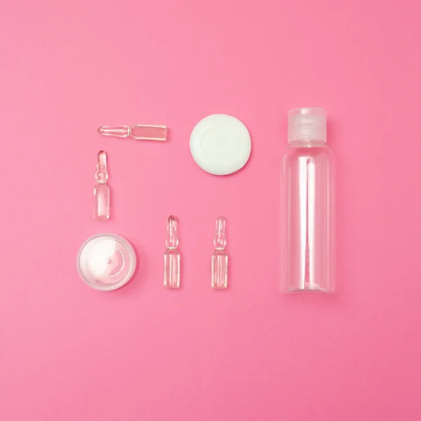 Güzellik kozmetik cam şişe, ampul ve kap. Damgalamak için uygun. Pembe arka plan kavramının üzerine yaslan.