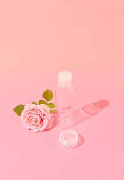 Güzellik kozmetik cam şişe, kap ve pembe gül. Damgalamak için uygun. Pastel pembe arkaplanda ön görünüm.