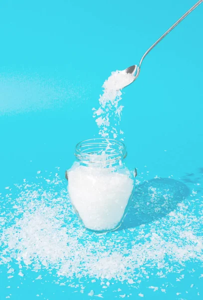 Mavi arka planlı kavanoza kar kırıntıları dökmek için yaratıcı bir kış fikri. Yeni yıl için en düşük fikir.