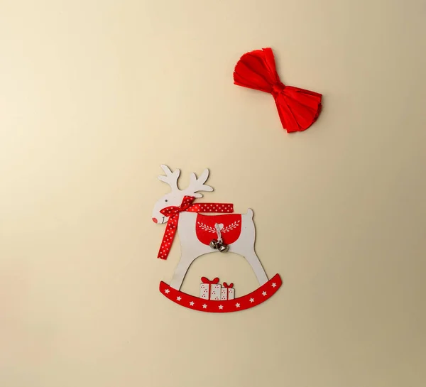 Kırmızı fiyonklu beyaz bir yüzey üzerinde bir ren geyiği. Noel kartı için minimalist bir fikir.