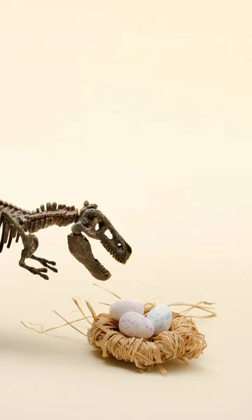 T-Rex 'le Paskalya kompozisyonu ve bir yuvada yumurtalar. Bej arka planda dinozor dünyası.
