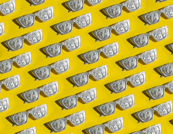 Sarı arka planda alüminyum folyoyla güneş gözlüğü deseni. Asgari yaz ve güneş koruma kavramı.