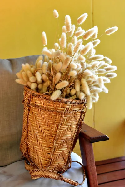 Küçük siyah sepetteki çim dalları, açık arkaplandaki ahşap masada bir brach daha. Uzayı kopyala İç kısımdaki doğal malzemeler..