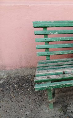 Pembe bir duvara yaslanmış yeşil bir bank