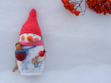 Kırmızı şapkalı, çiçekli ve beyaz arka planda palamutlu bir kardan adam.