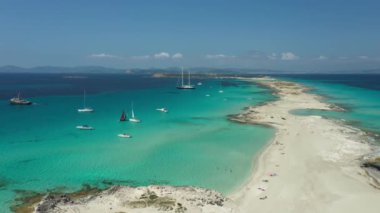 Formentera 'daki Illetes plajı, turkuaz sular ve beyaz kum. Yazın kıyılarına demirlemiş tekne ve yatlar. İnsansız hava aracı görüntüleri.