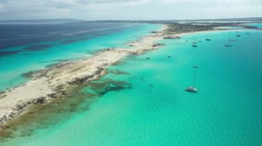 Formentera 'daki Illetes plajı, turkuaz sular ve beyaz kum. Yazın kıyılarına demirlemiş tekne ve yatlar. İnsansız hava aracı görüntüleri.