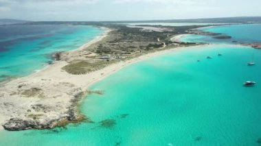 Formentera 'daki Illetes plajı, turkuaz sular ve beyaz kum. Yazın kıyılarına demirlemiş tekne ve yatlar. İnsansız hava aracı görüntüleri.