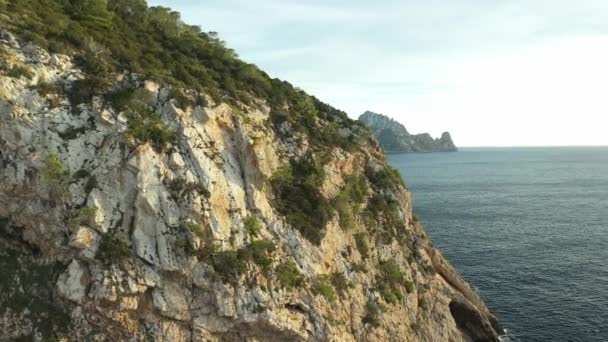La isla de Es Vedra que aparece detrás de un acantilado frente a la costa de Ibiza. Imágenes de drones — Vídeos de Stock