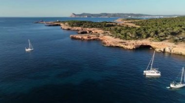 İbiza Cala Comte plajı Baleares 'in insansız hava aracı sahili. Tekneler, yatlar ve katamaranlar kıyılarda yüzüyor.