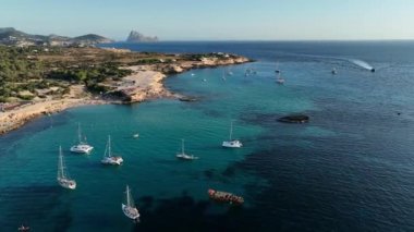 Aerial view from drone of a stunning beach in Ibiza Cala Comte beach Baleares Boats yachts and catamarans ply its shores