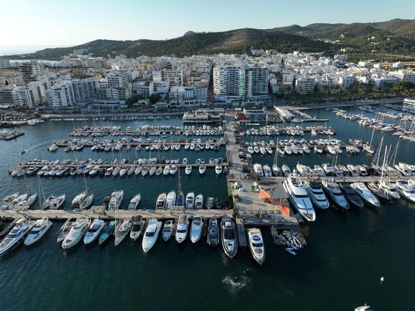 Yat limanında tekne ve yelkenli dolu dubaların havadan görünüşü şehre bakıyor. İbiza,