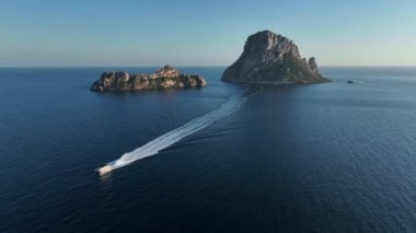 Aerial video of Es Vedra and Es Vedranell islands in Ibiza, yacht returning from visiting it sailing the sea. Drone footage.