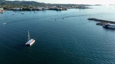 Leaving the port at sunset. Catamaran arriving at port. Drone view. Ibiza